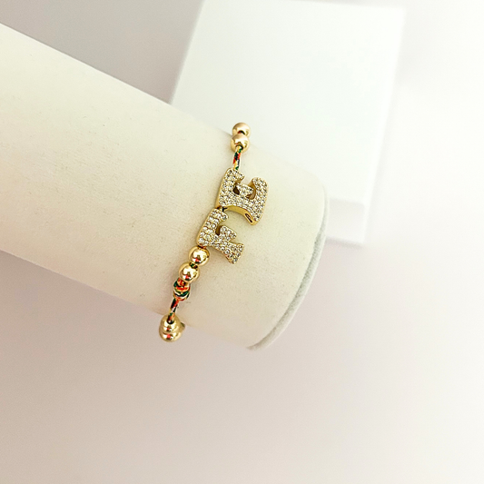 Delicate faith bracelet with crystal-studded “FE” charm, gold beads, and multicolor braided details for a meaningful touch.