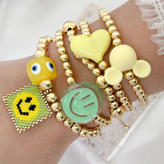 Bracelets with emoji charms on a wrist against a white background
