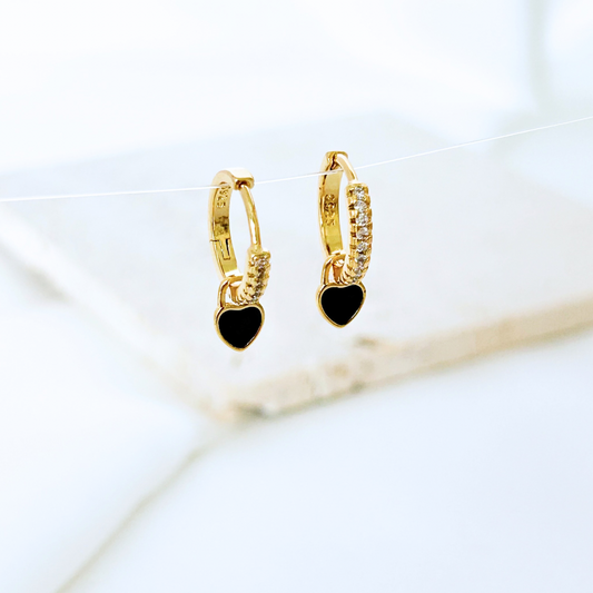 Gold hoop earrings with black heart charms on a white background