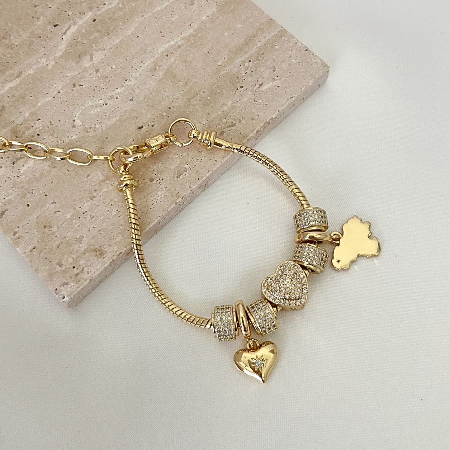 Adjustable charm bracelet inspired by Venezuela, crafted with gold-tone details, shimmering pavé charms, and heart accents for a meaningful everyday accessory.