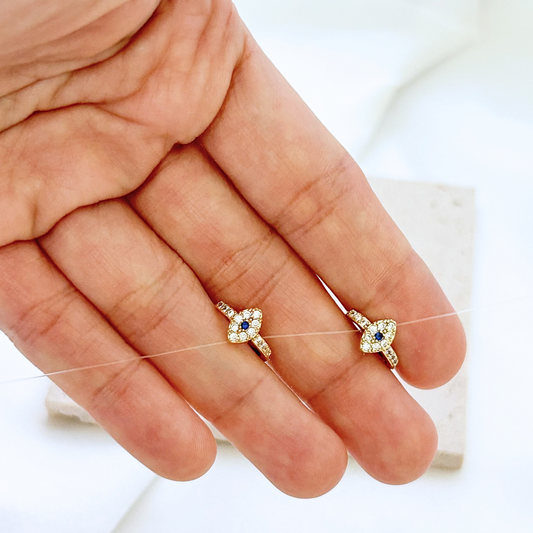 Two diamond-studded earrings held between fingers against a white background