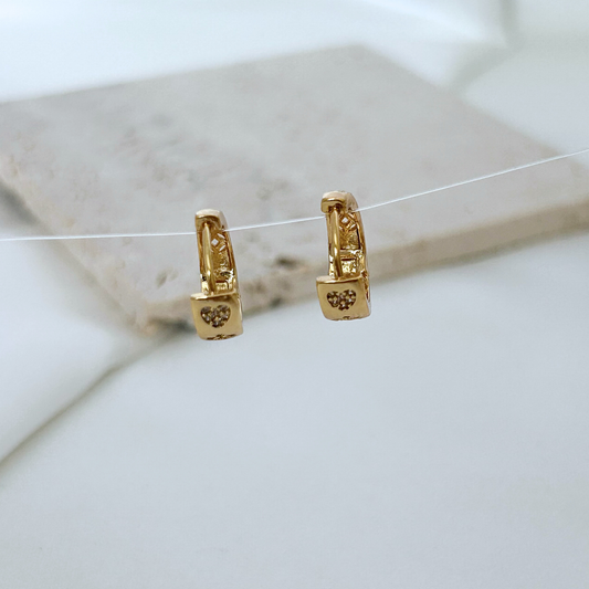 Gold hoop earrings with intricate designs on a light background