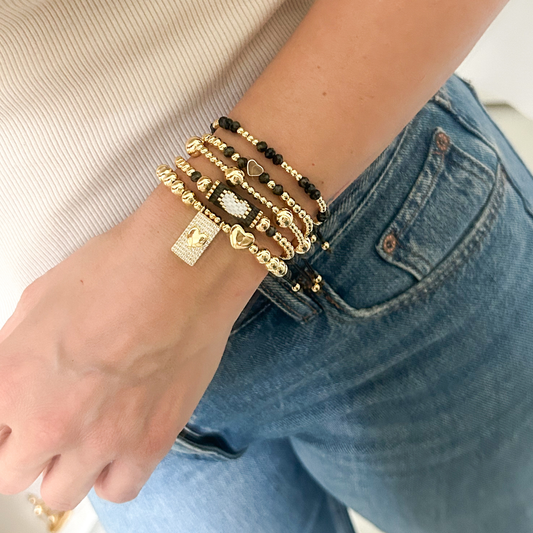 Black gold bold heart bracelet set with pavé charm worn on wrist