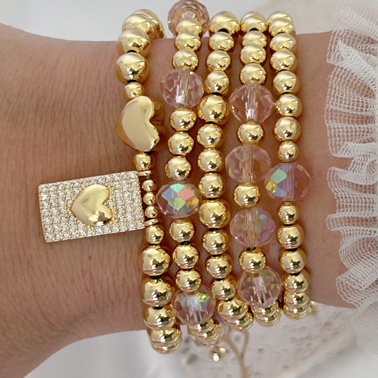 Gold beaded bracelet with heart-shaped clasp on a wrist