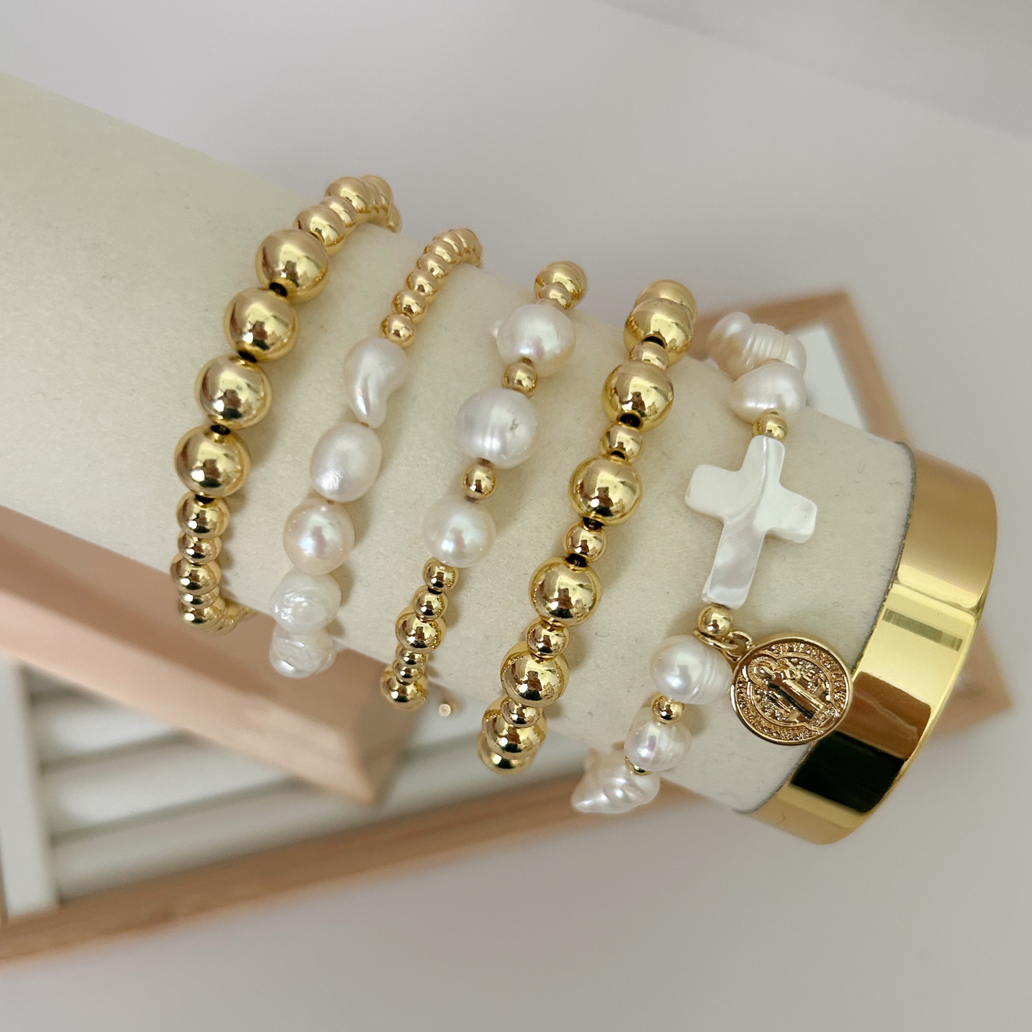 Saint Benedict pearl cross gold bracelet set displayed on jewelry stand