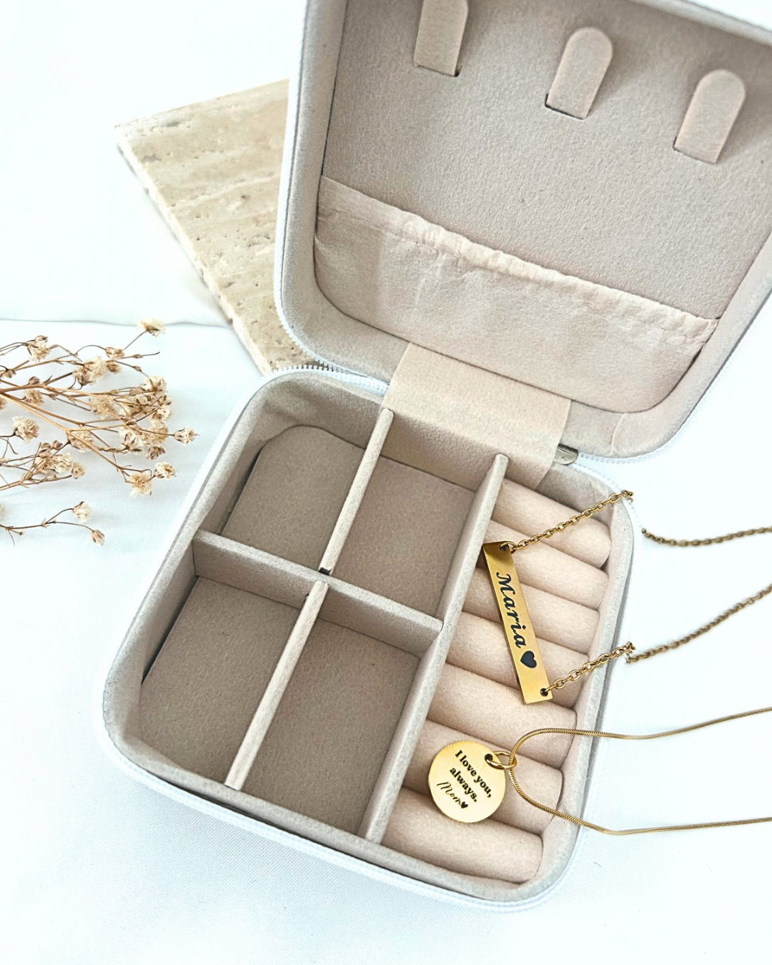 Personalized gold necklace with engraved name bar and round message pendant displayed on a cream jewelry tray.