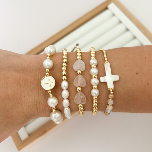 Gold faith bracelet stack with pearl cross medallion styled on wrist
