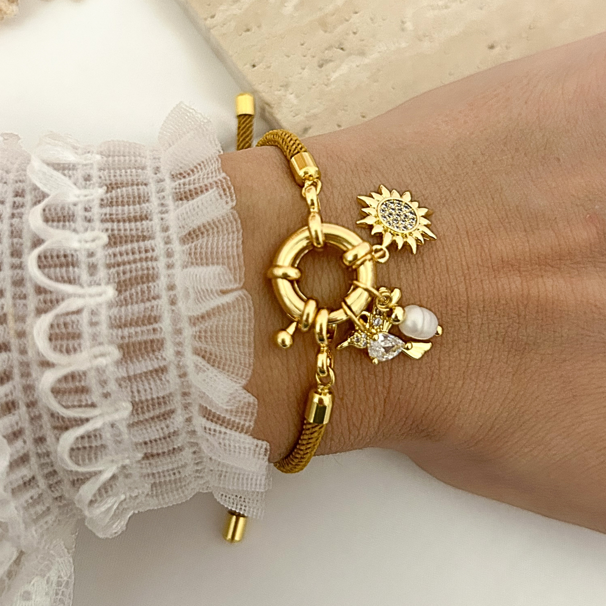 Adjustable cord bracelet with sun charm, hummingbird charm, and pearl accent in copper