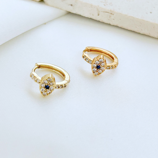 Gold hoop earrings with blue gemstones on a white surface