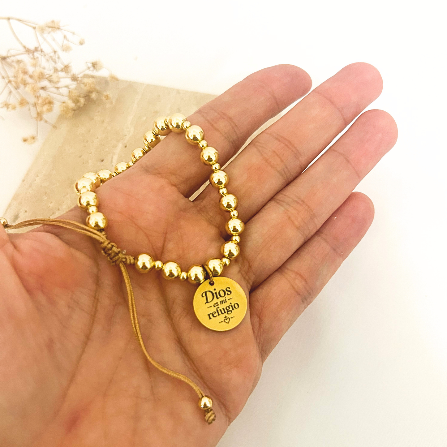 Gold bead bracelet with faith charm held in hand