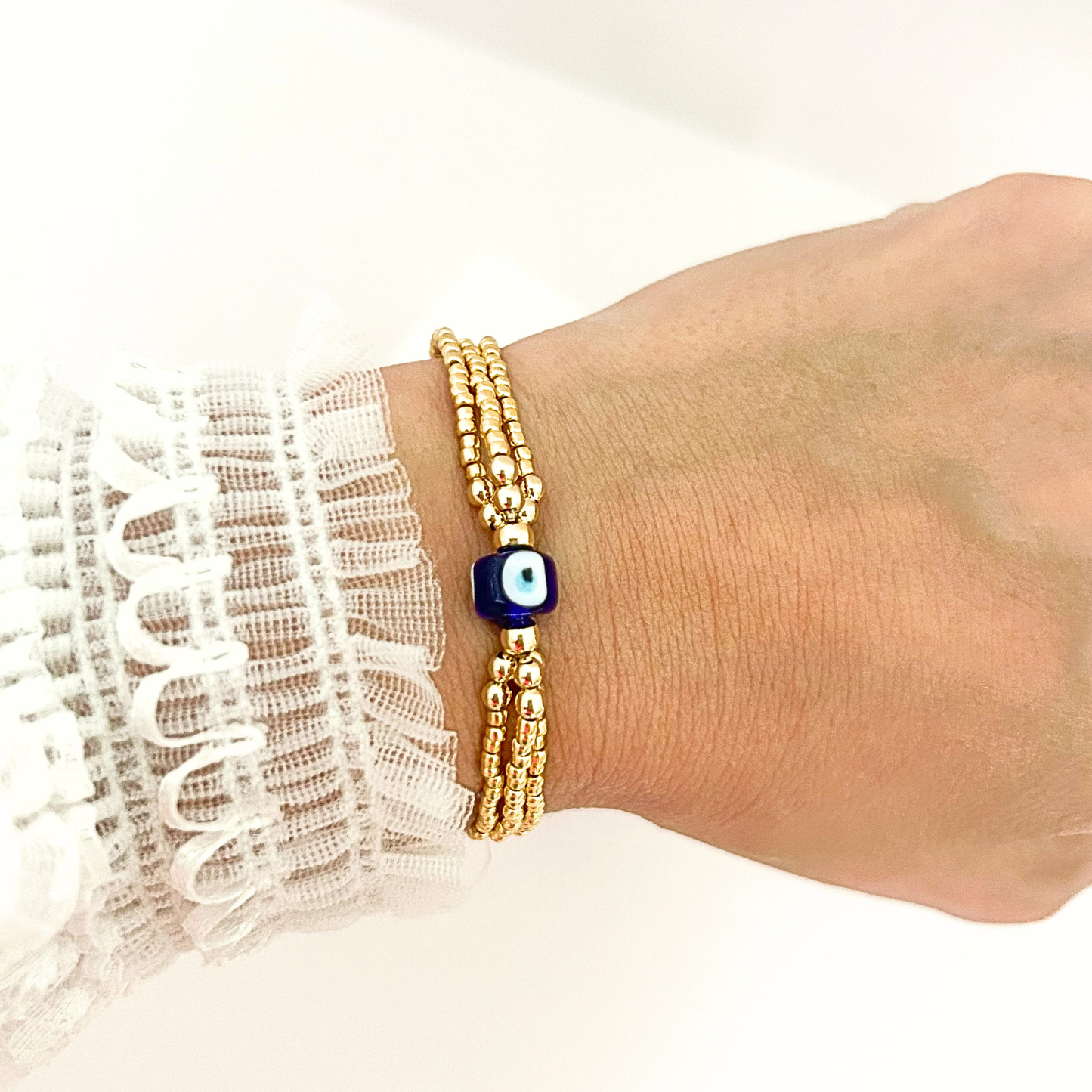 Minimalist evil eye bracelet with gold beads and a protective blue glass charm, perfect for stacking or wearing alone.