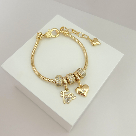Gold-tone charm bracelet with heart and faith charms, crystal accents, and elegant snake chain design.