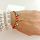 Elegant adjustable bracelet with a red cord, crystal cross centerpiece, protective evil eye charm, and gold-tone details.