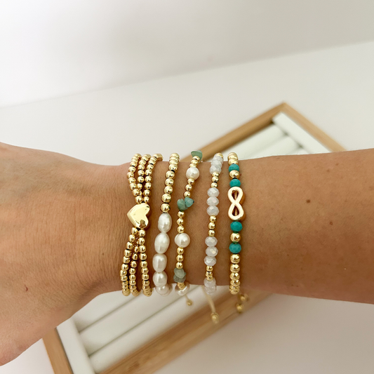 Turquoise pearl infinity gold bracelet stack styled on wrist with display