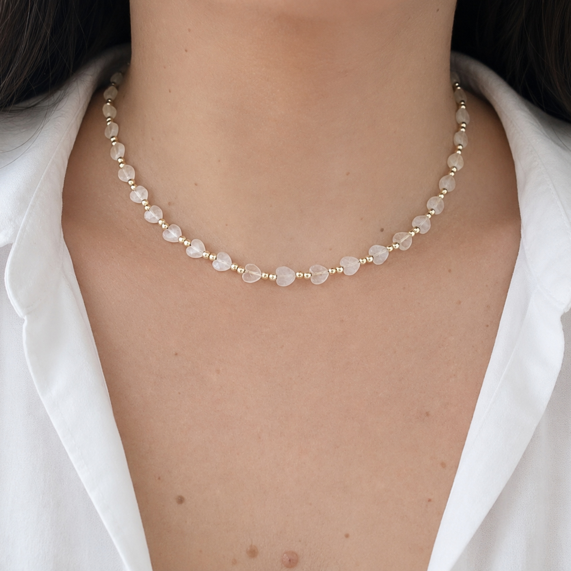 Elegant heart-shaped bead necklace worn on a model, combining soft translucent beads with gold-tone details for a romantic everyday look.