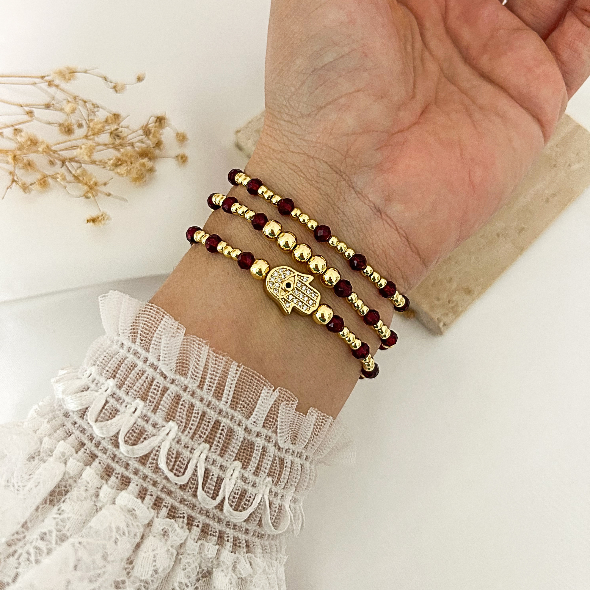 Hamsa protection bracelet stack with garnet-color crystal beads worn on wrist