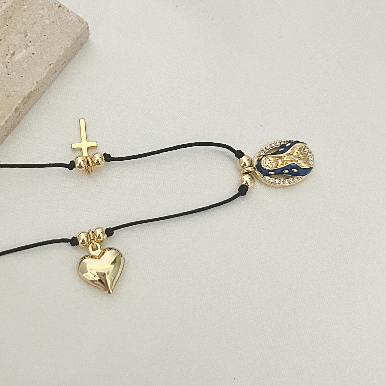 Close-up of a handcrafted spiritual necklace showcasing gold-tone charms on a minimalist black cord, designed for everyday wear and meaningful gifting.