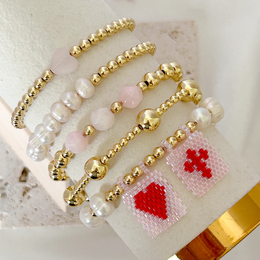Beaded bracelet with heart and cross charms on a textured surface