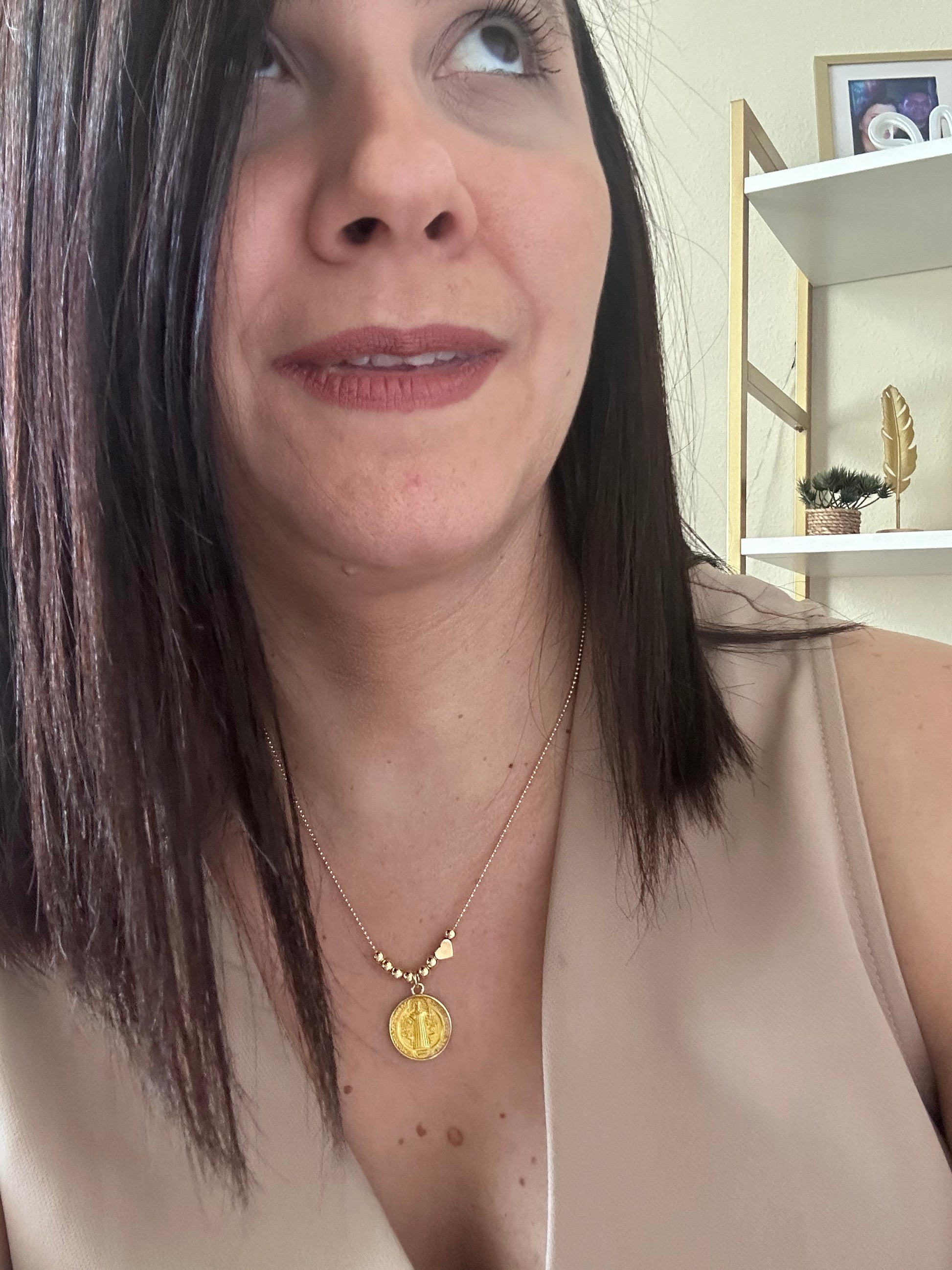 Close-up of a person wearing a gold necklace with a pendant.