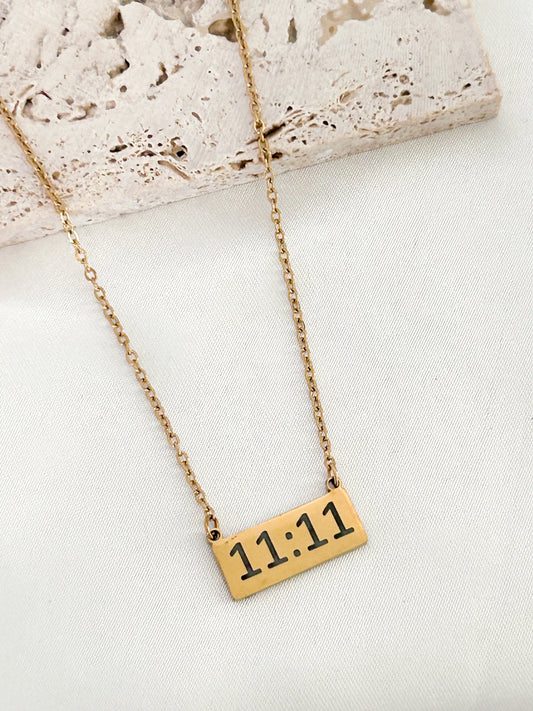 Gold necklace with a rectangular pendant displaying '11:11' on a light background
