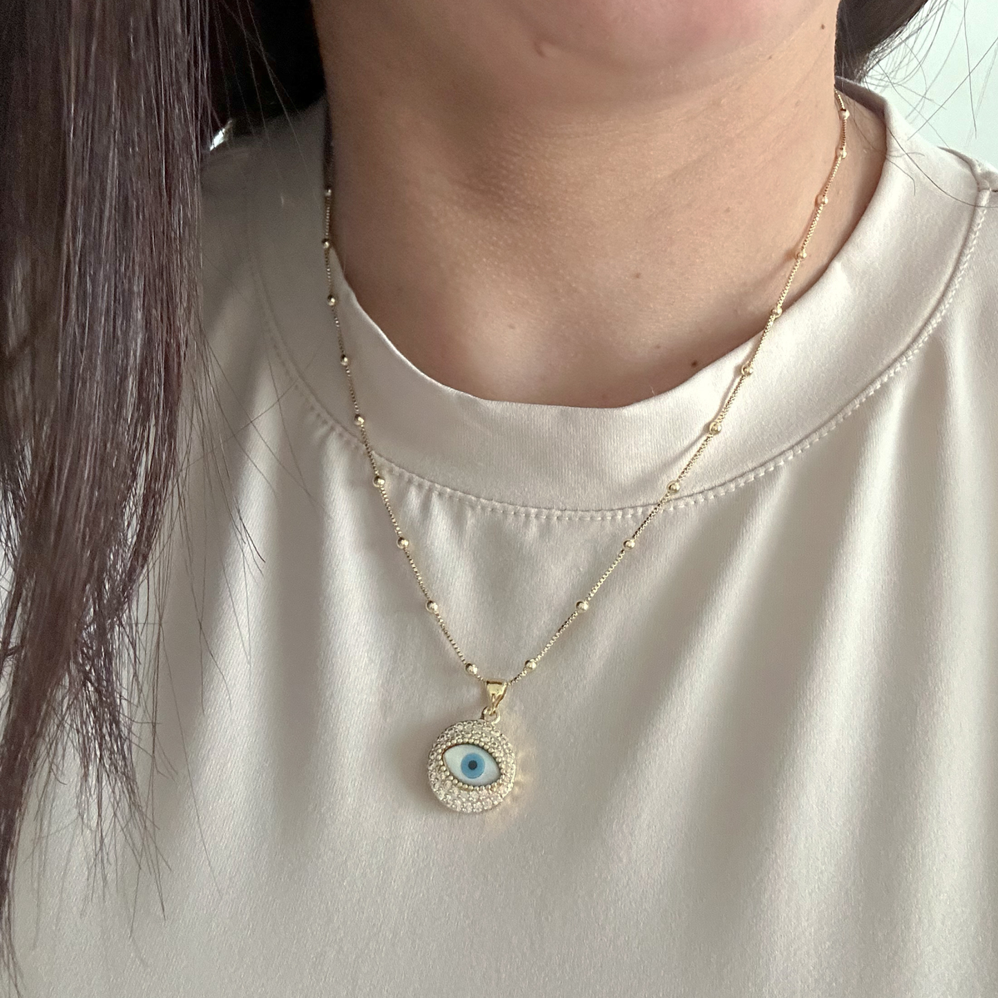 Gold evil eye pendant necklace with blue enamel and zirconia halo on gold chain on white background — Citrika