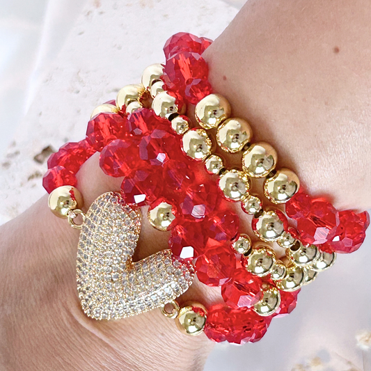 Close-up of a hand wearing two beaded bracelets with red and gold beads.