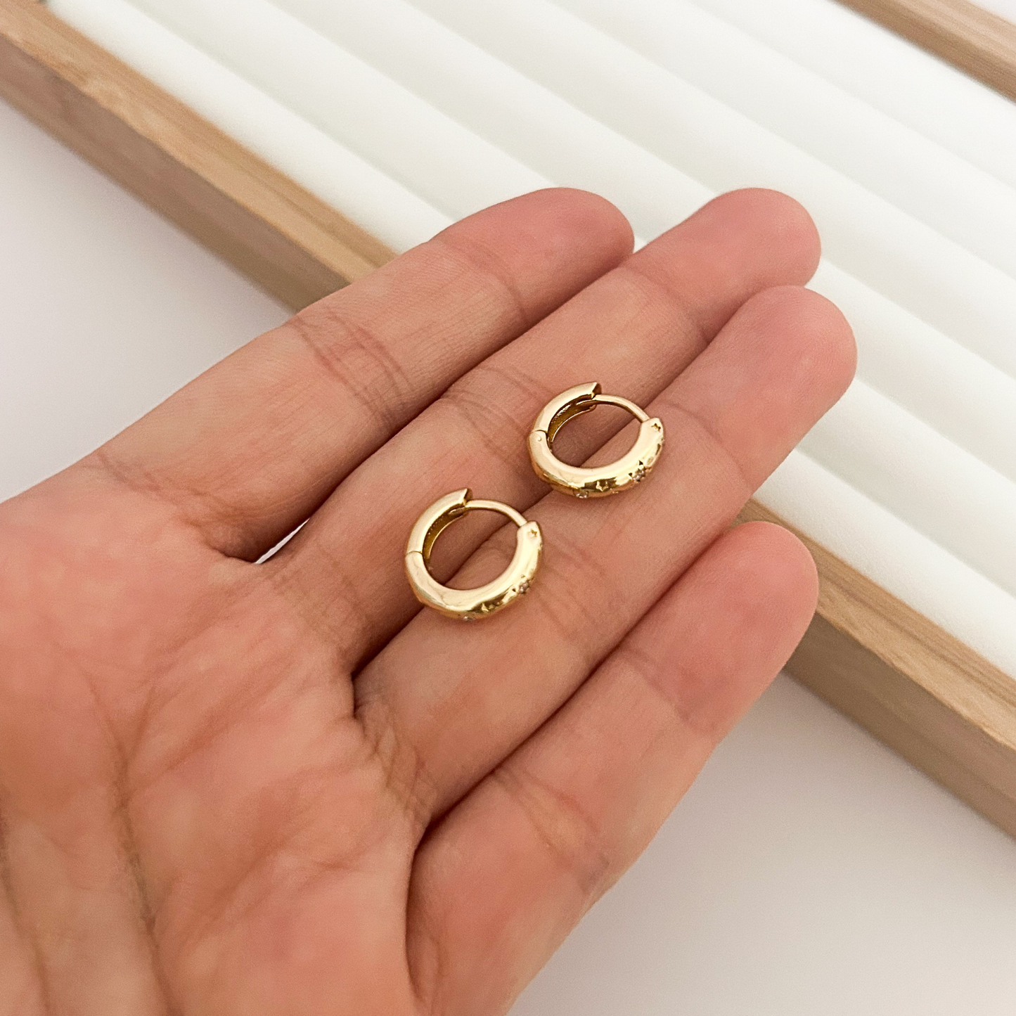 Pair of 18K gold plated small chunky huggie hoop earrings held in hand