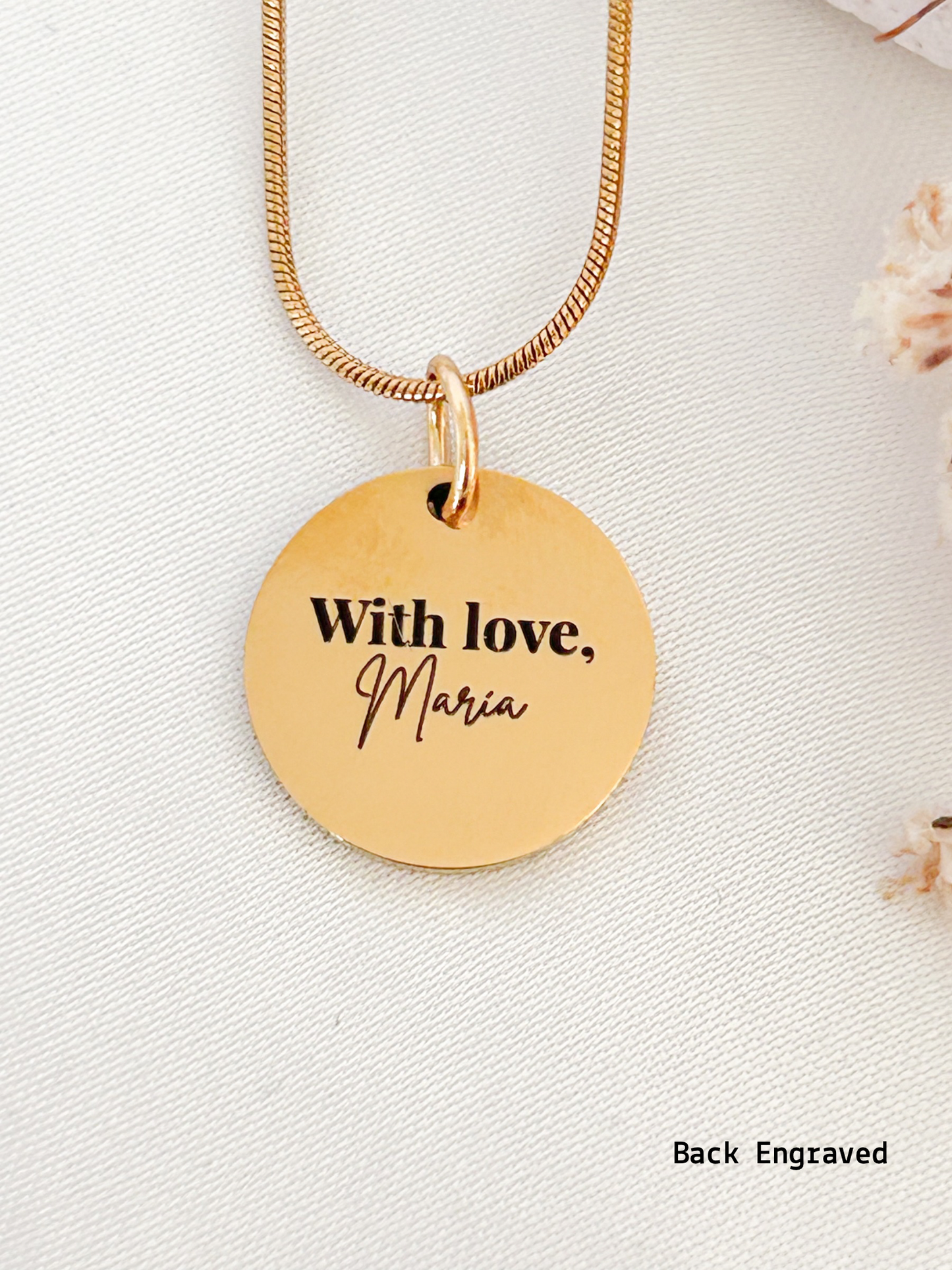 Gold necklace with a round pendant engraved with 'With love, Maria' on a light background.