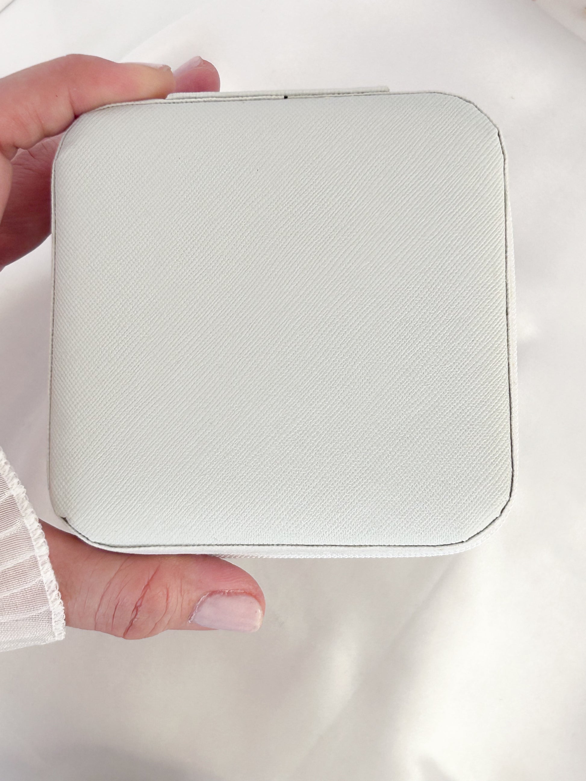 Hand holding a small white rectangular device against a light background