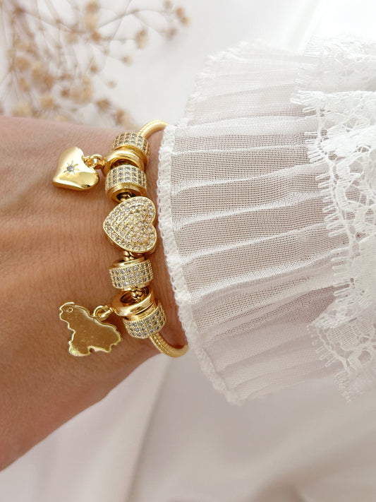 Gold bracelet with heart-shaped charms on a wrist against a white lace background
