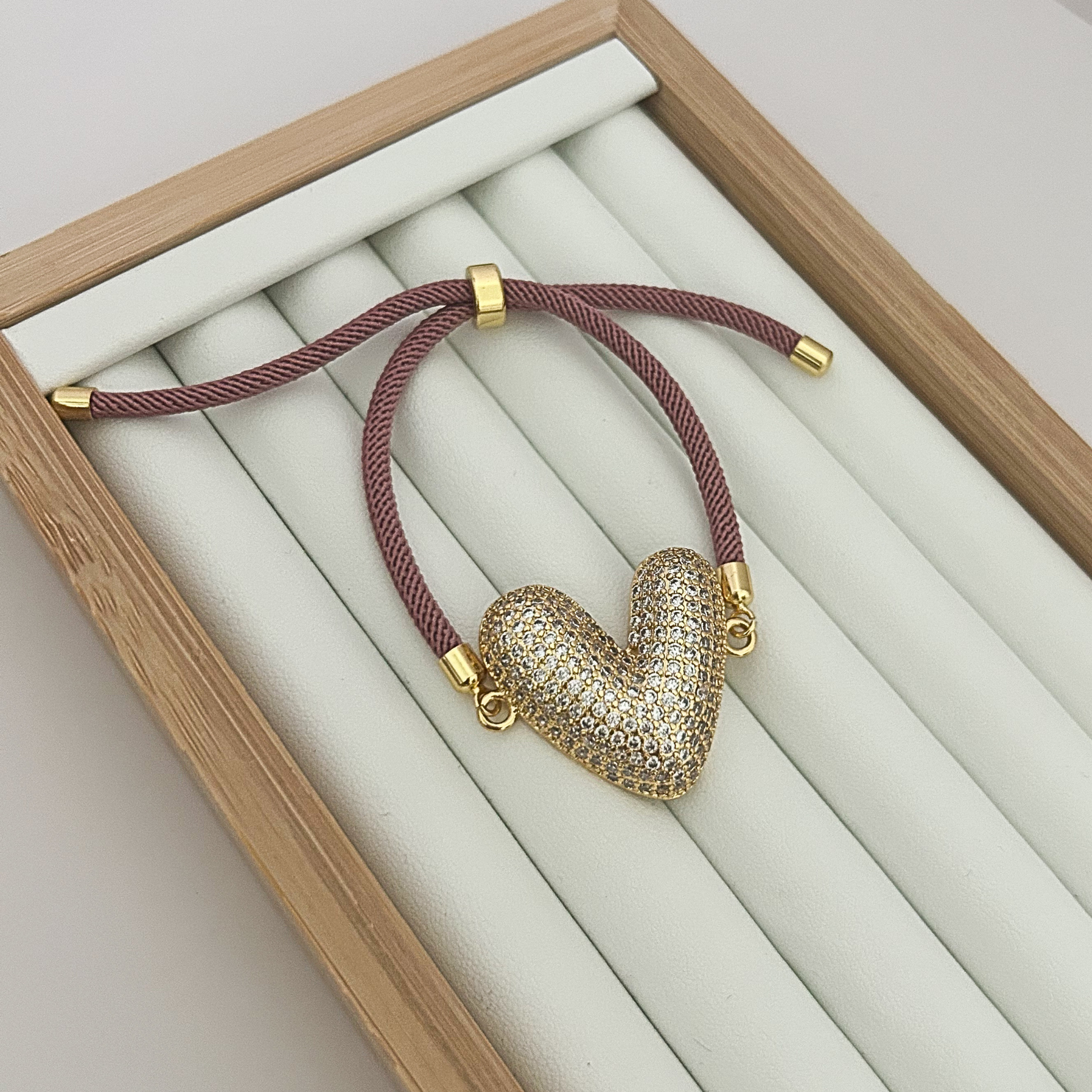 Adjustable burgundy cord bracelet with gold rhinestone heart charm.