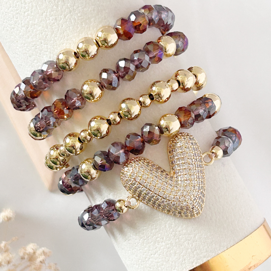 Beaded bracelet with a gold heart charm on a white surface