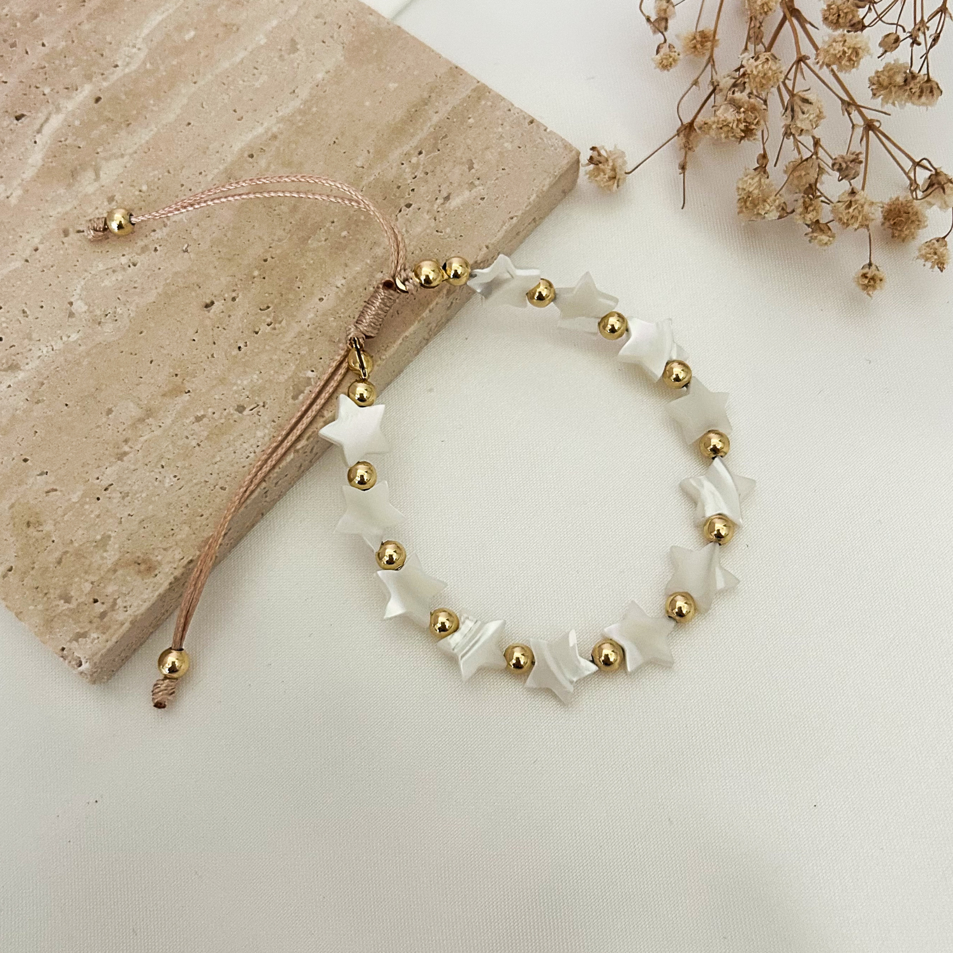 Minimalist star bracelet crafted with white mother-of-pearl style star beads and gold-tone details, designed for everyday wear and easy adjustment.