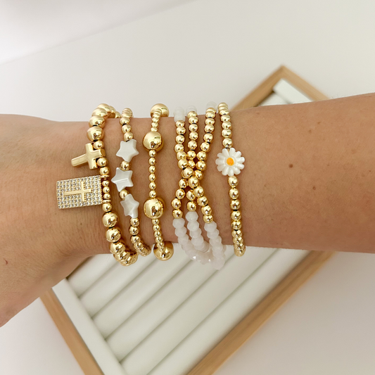White gold faith bracelet stack with daisy and cross charms styled on wrist