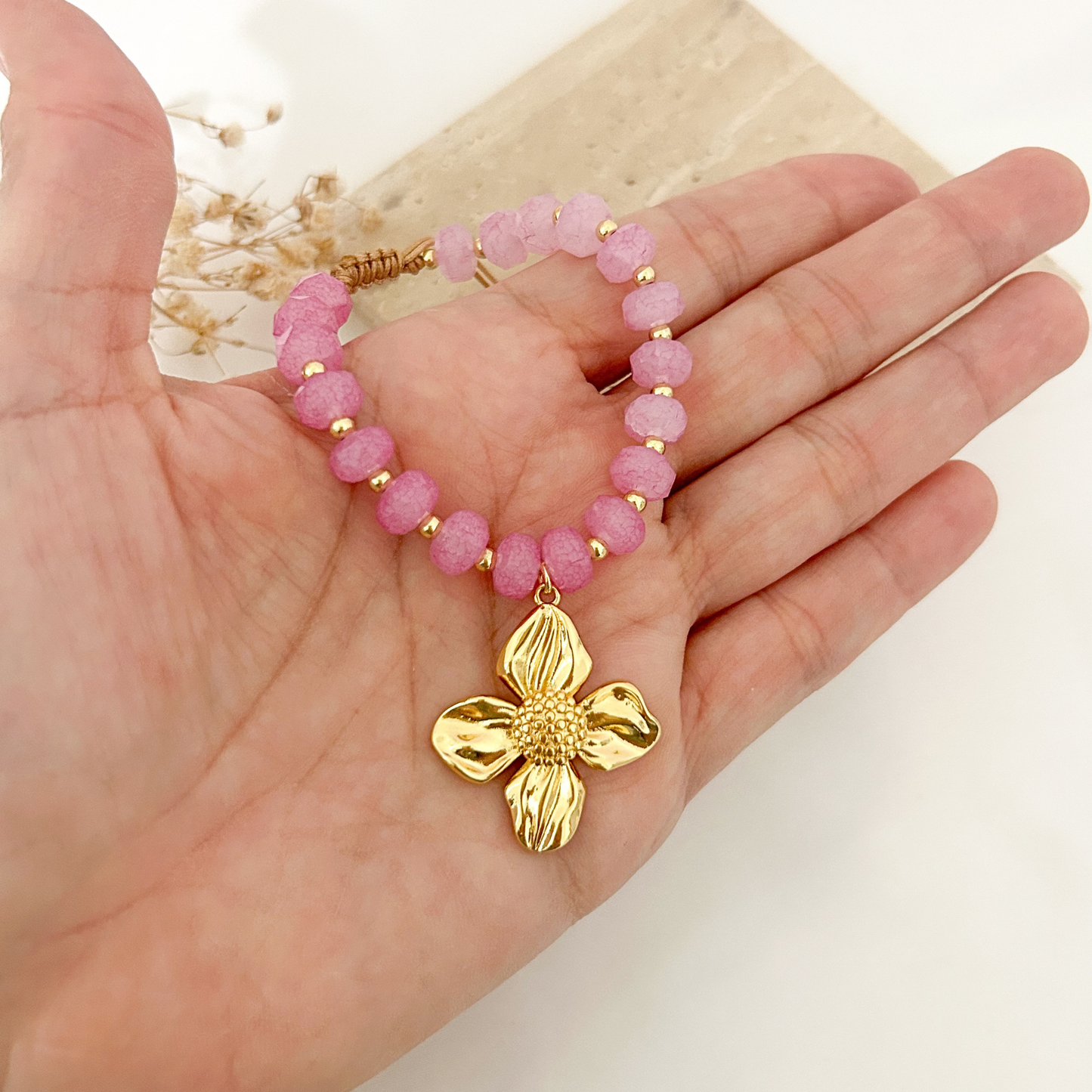 Magenta crystal bracelet with flower charm held in hand