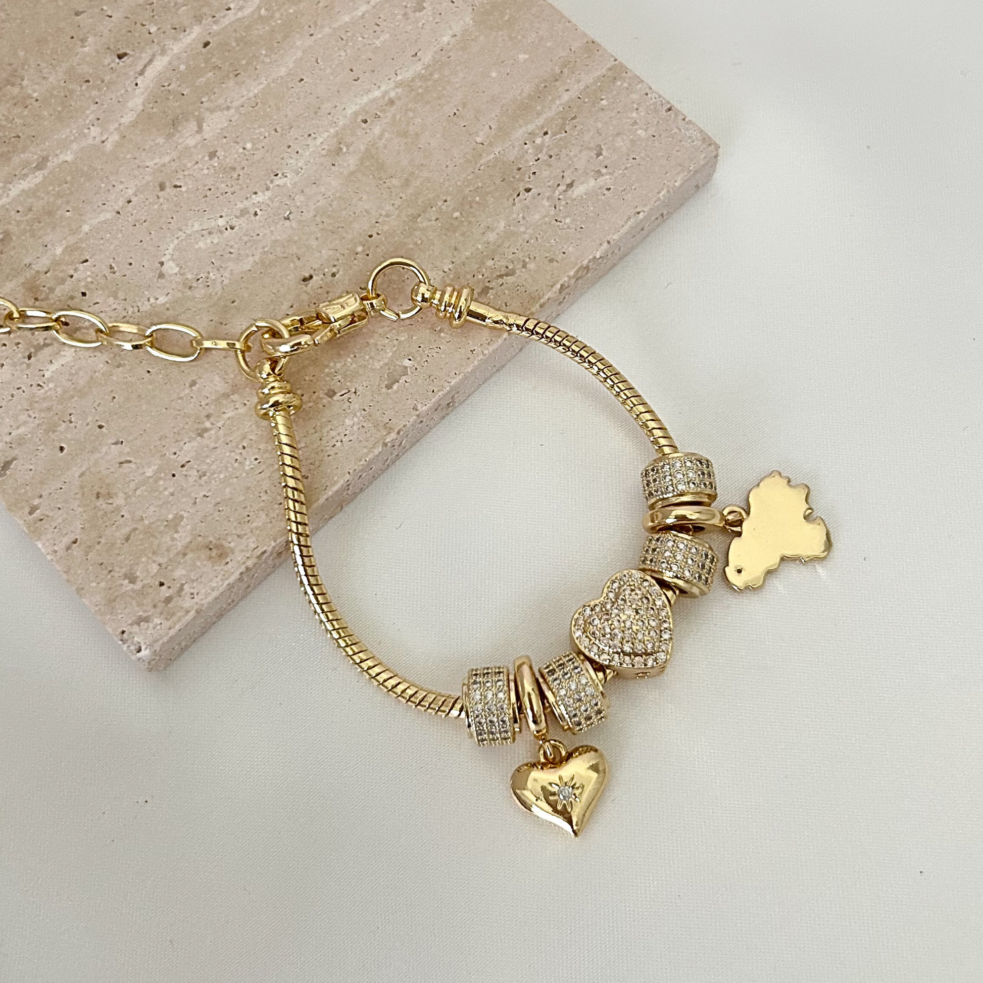 Adjustable charm bracelet inspired by Venezuela, crafted with gold-tone details, shimmering pavé charms, and heart accents for a meaningful everyday accessory.
