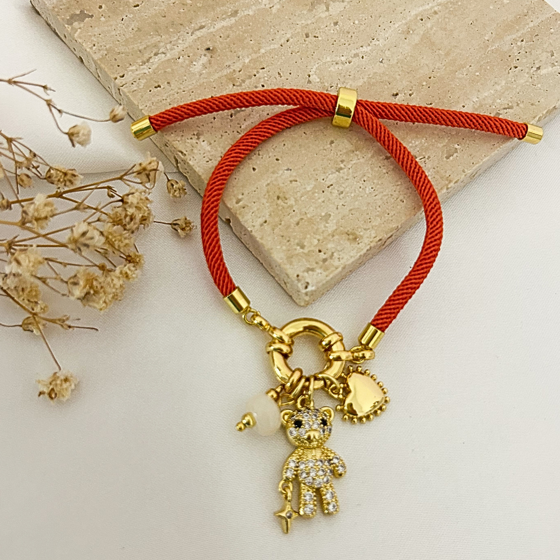 Orange cord bracelet with teddy bear charm and heart charm