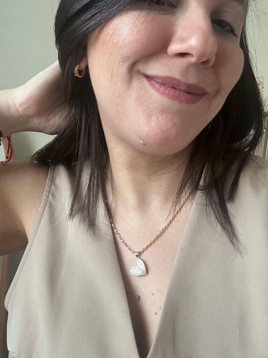 Close-up of a person wearing a necklace with a heart pendant.