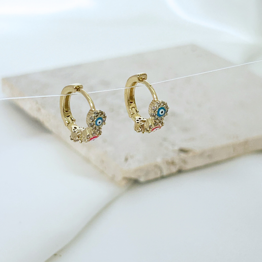 Gold hoop earrings with blue gemstones on a white surface