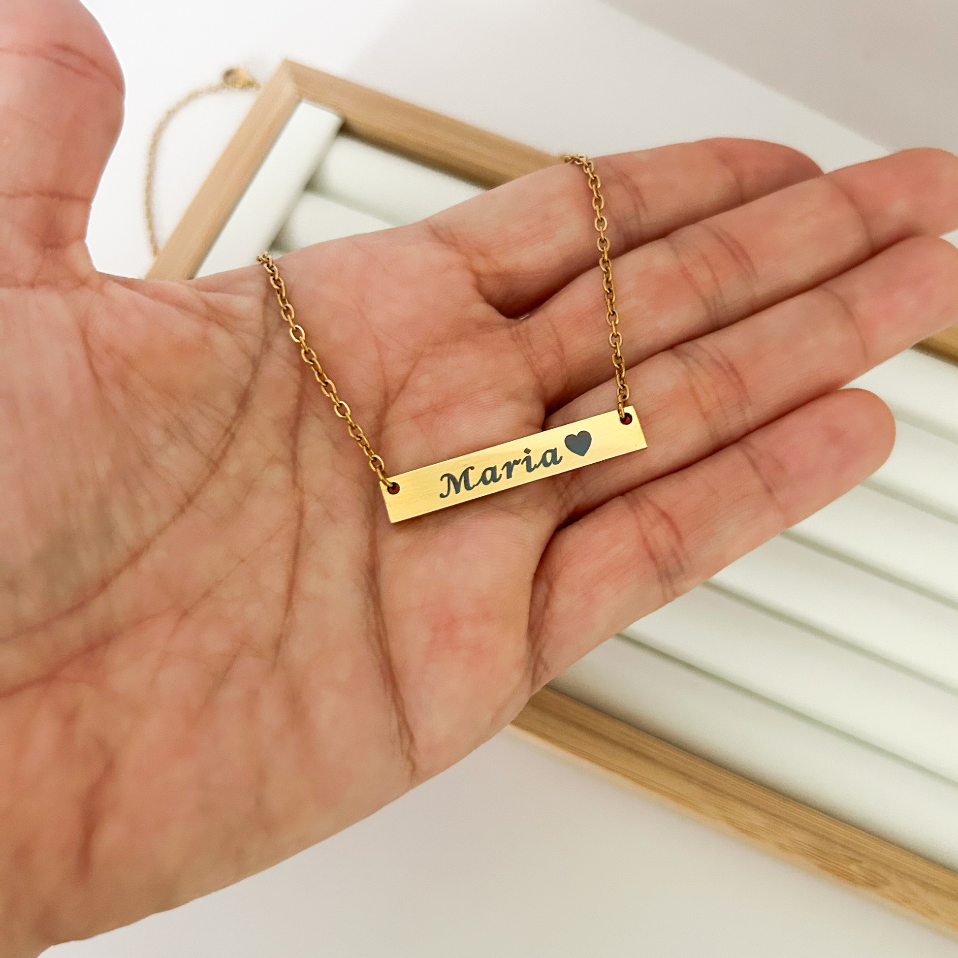 Gold necklace with 'Maria' engraved on a hand