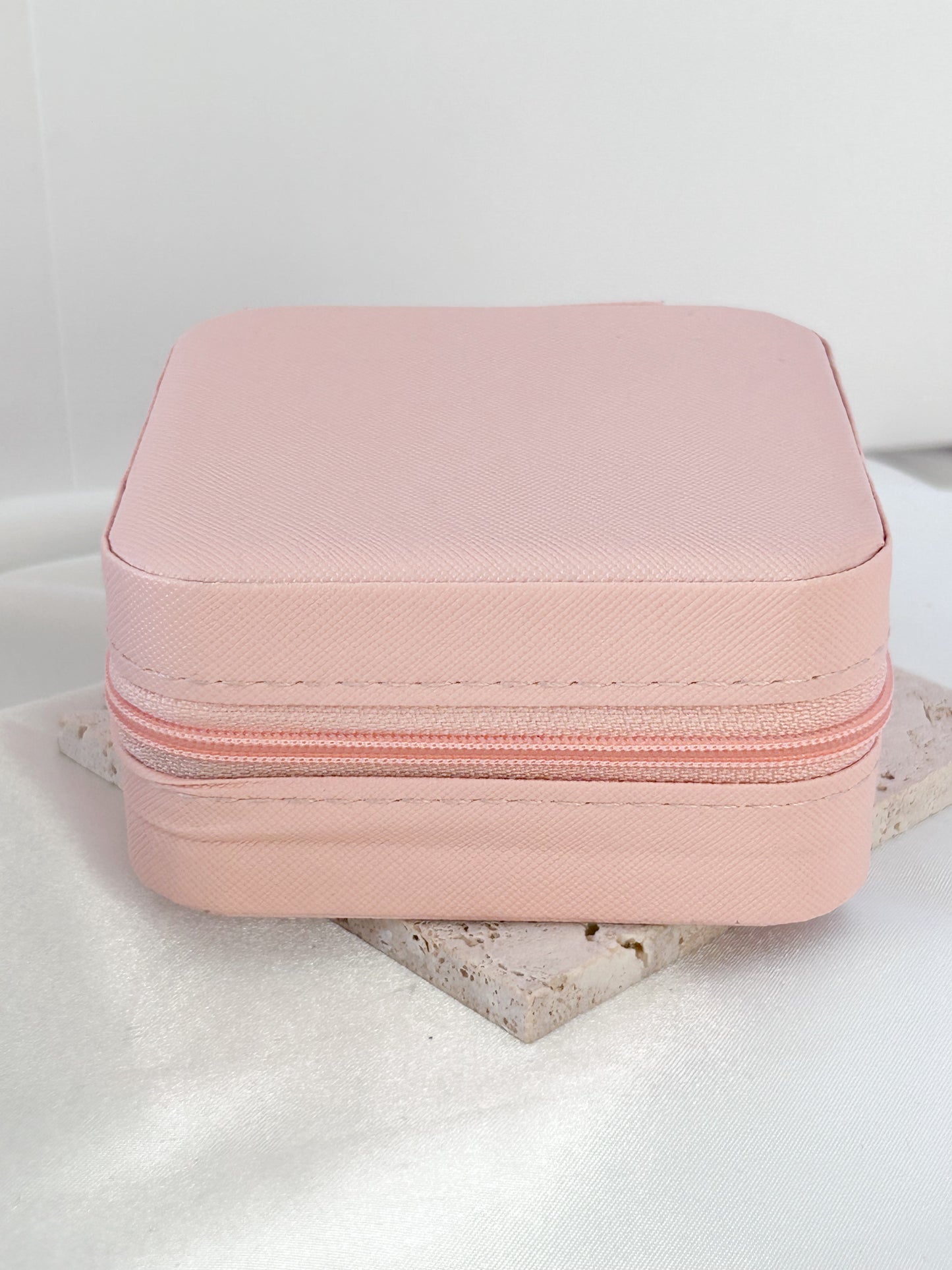 Pink jewelry box with a zipper on a white surface