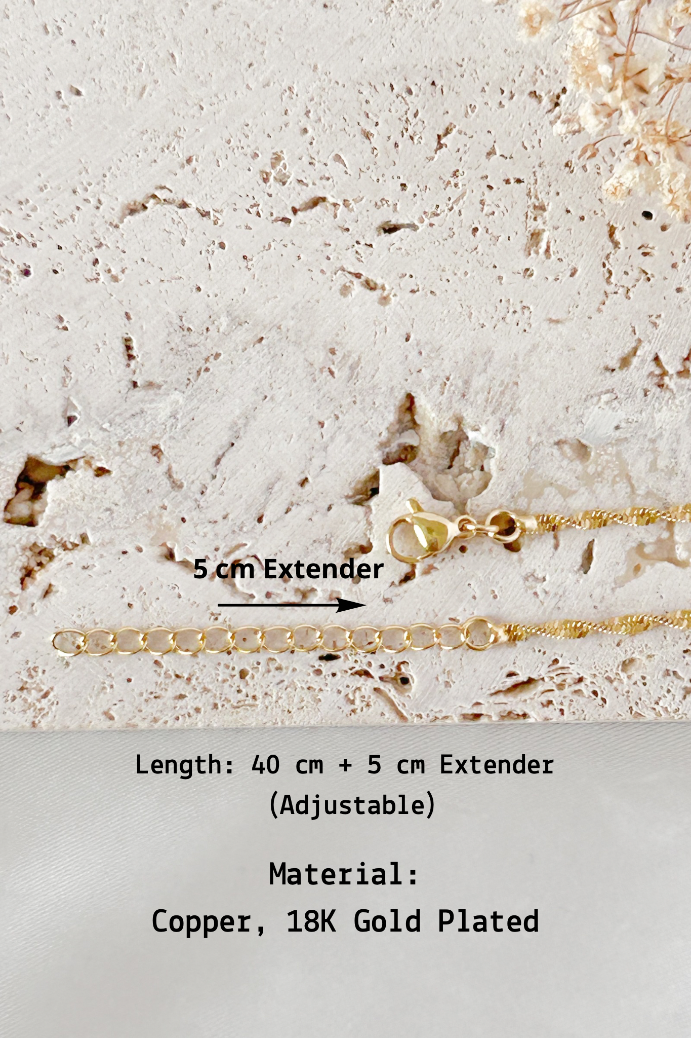 Gold necklace with 5 cm extender on a textured surface