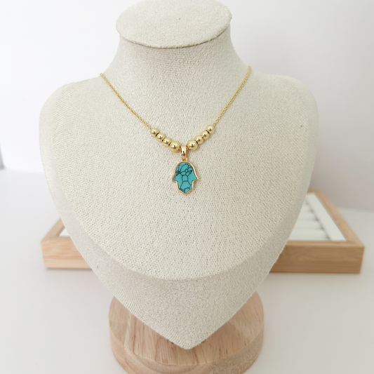 Gold beaded necklace with turquoise Hamsa hand pendant on linen jewelry bust — Citrika