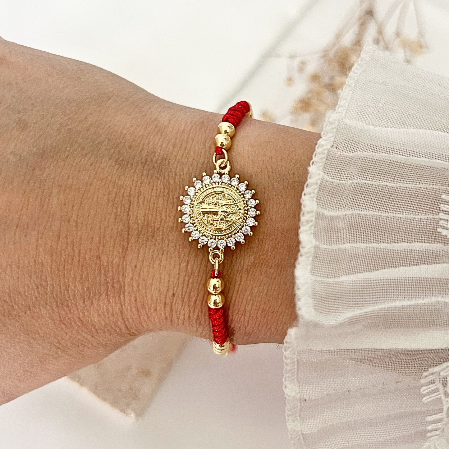Faith-inspired red cord bracelet with a detailed Saint Benedict charm, gold-tone accents, and an adjustable sliding closure for a comfortable fit.