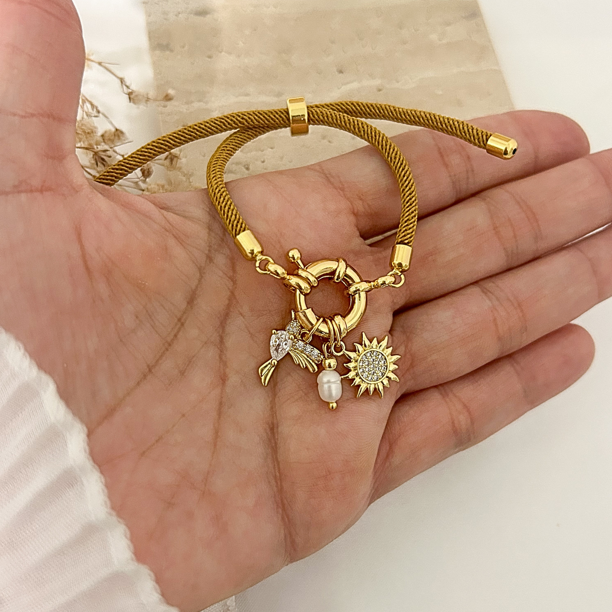 Adjustable cord bracelet with sun charm, hummingbird charm, and pearl accent in copper
