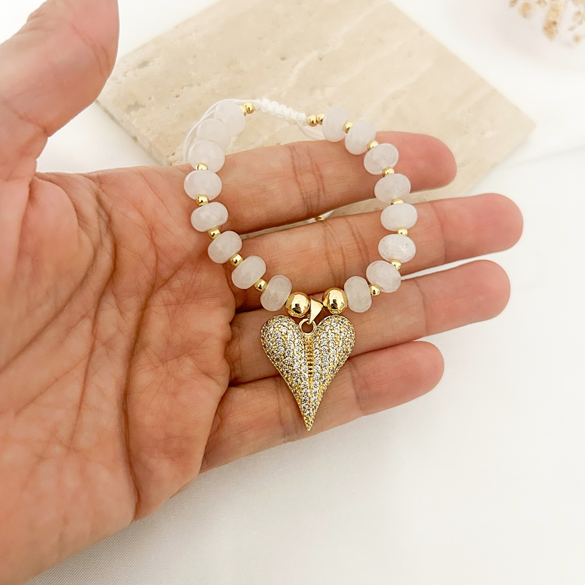 Hand holding moonstone beaded bracelet with pavé heart charm
