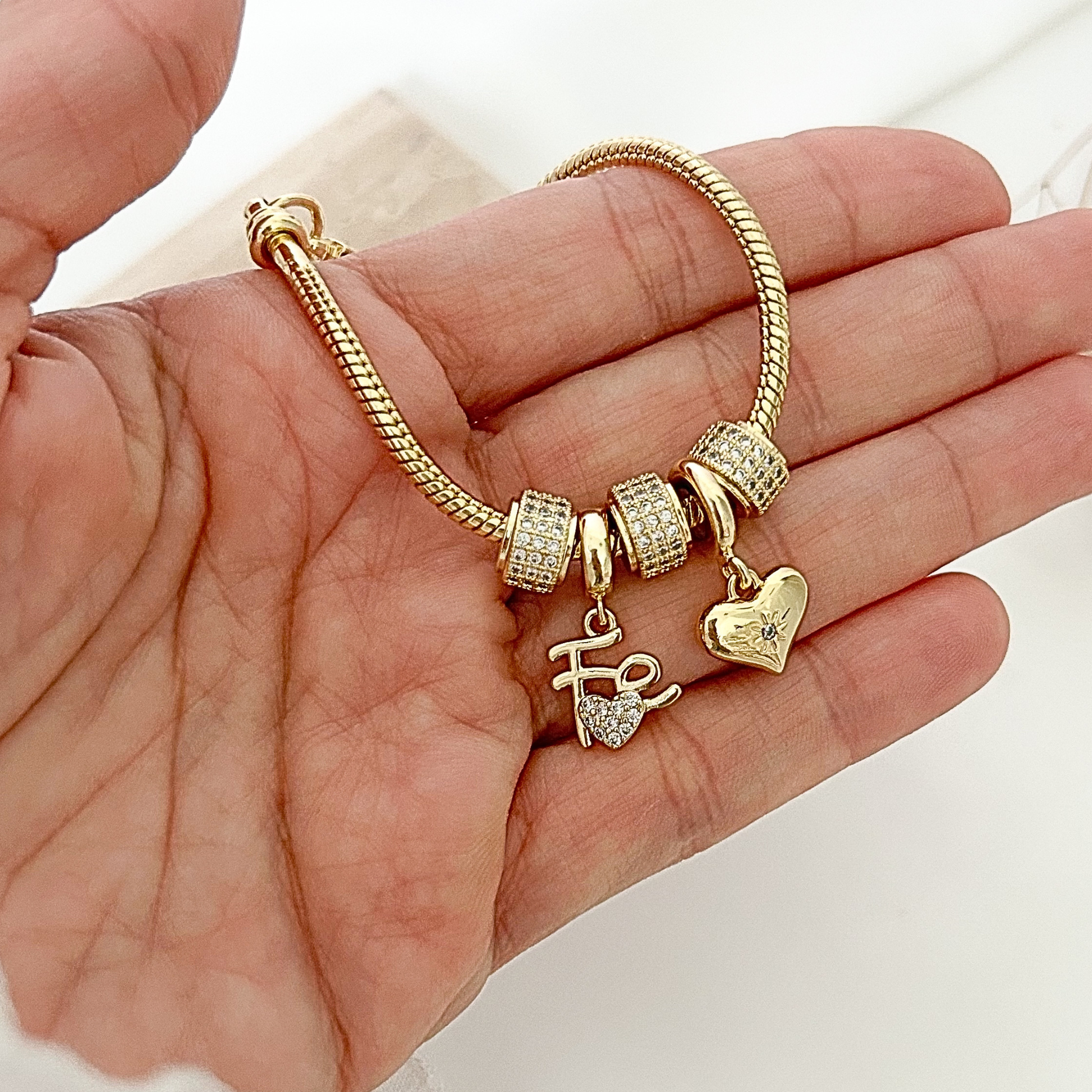 Close-up of a gold-tone bracelet with shimmering crystal charms, including a heart pendant and a “Hope” charm, showcasing its refined details and elegant finish.