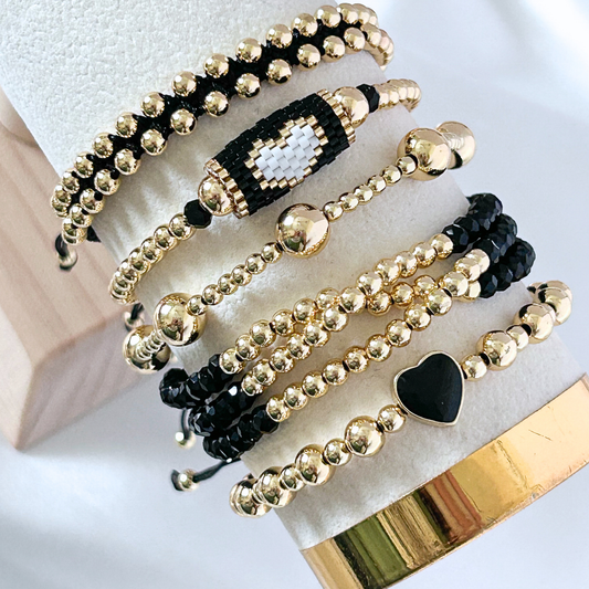 Set of gold and black beaded bracelets on a marble surface