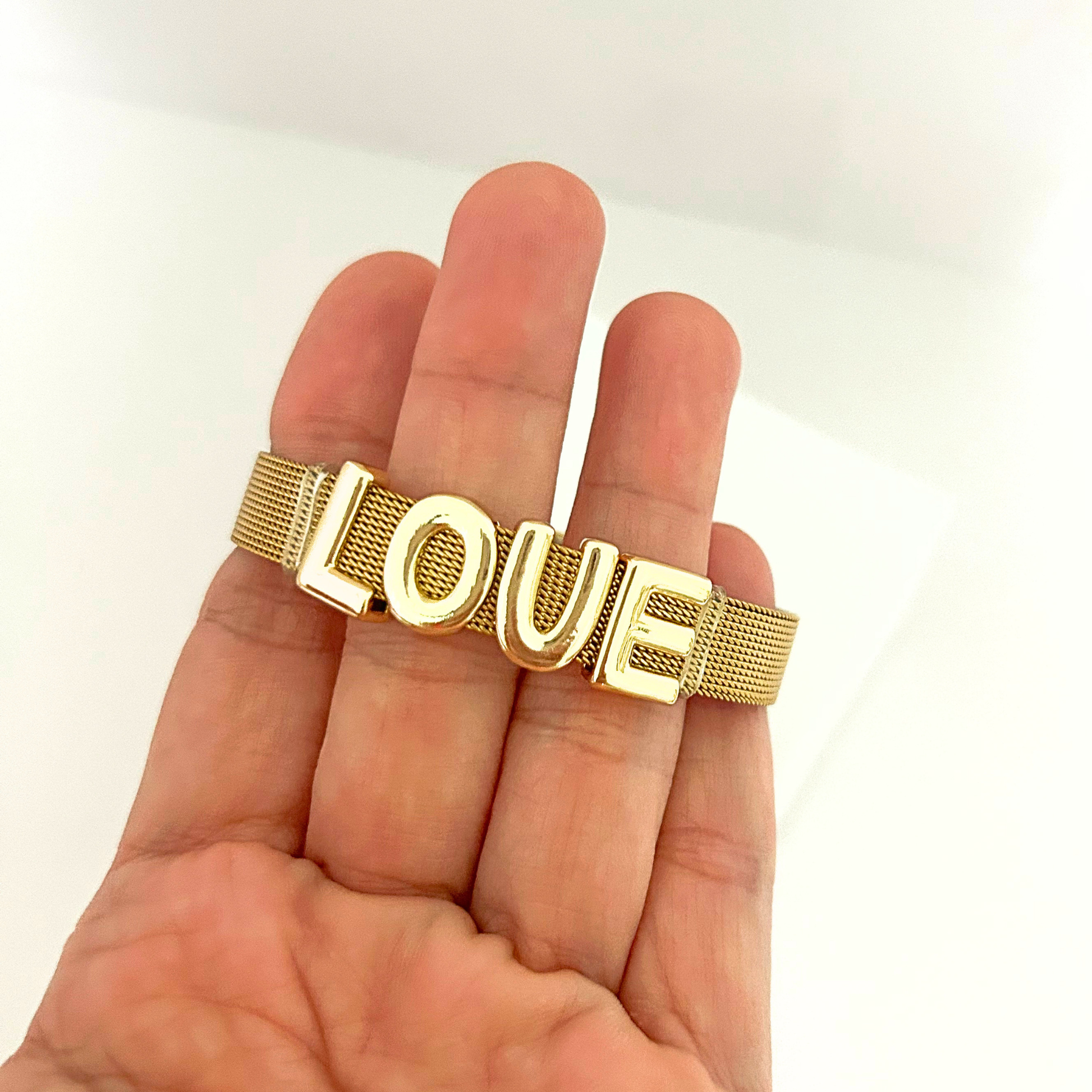 Close-up of a gold mesh bracelet with LOVE letters, highlighting its polished finish and adjustable fit.