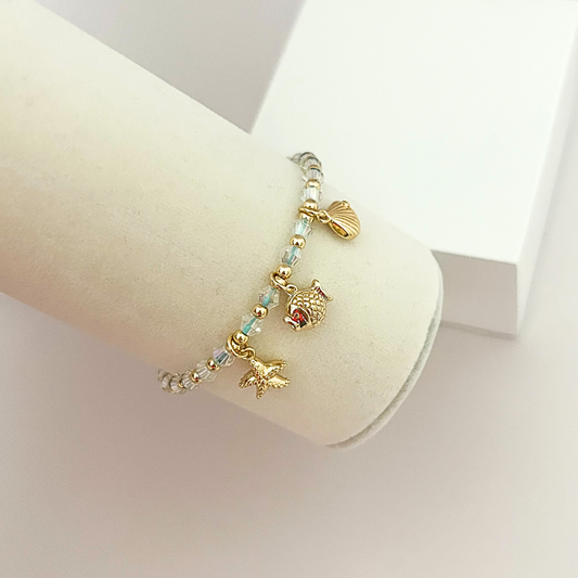 Coastal-themed bracelet with sparkling crystal beads and dangling ocean charms including a starfish, fish, and seashell.